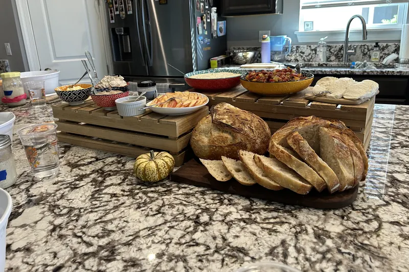 A spread of sourdough loaves and appetizers set out for class