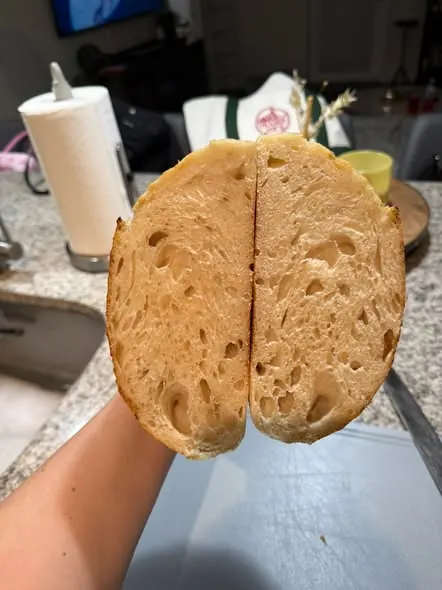 A student holding the cut halves of their sourdough loaf